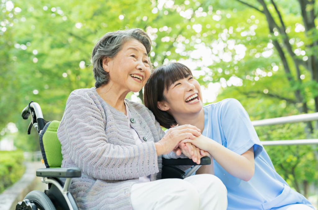 ヘルパーが車いすの利用者と公園でお出かけアテンドをする様子