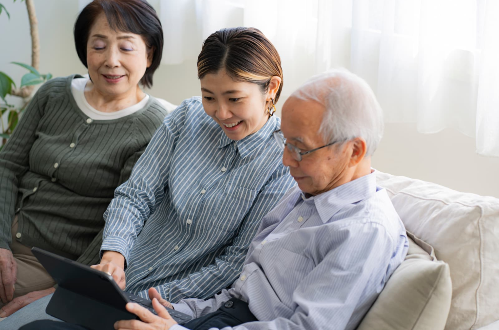 家族でタブレットを見ながら相談するシニア夫婦と娘