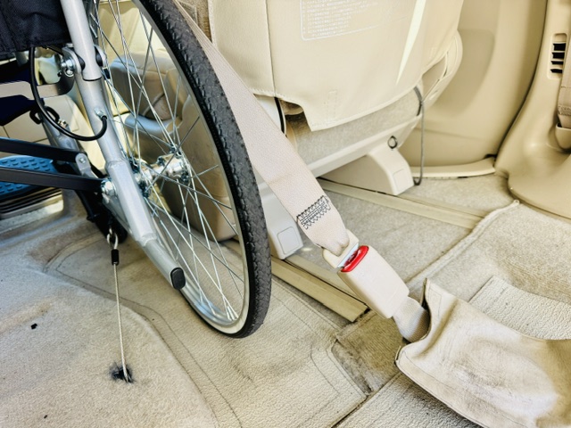 福祉介護タクシーの車両内に車いすを車床との固定とシートベルトをした様子